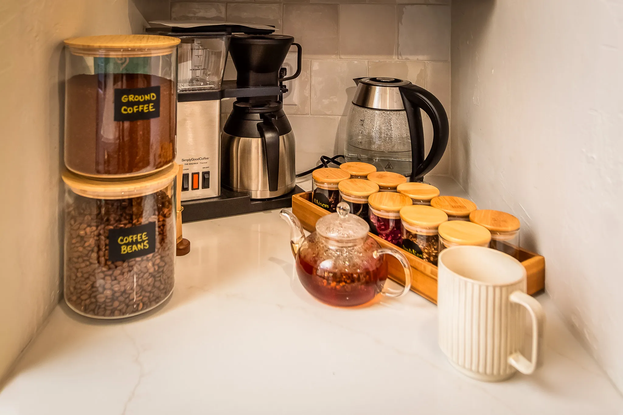 Coffee beans, loose leaf teas, and teapot on a white counter in a Sedona wellness retreat kitchen.