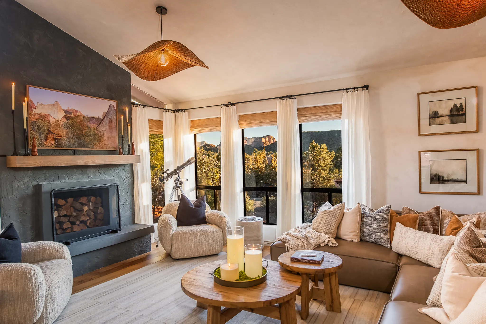 Modern living room with leather sofa, stone fireplace, and windows overlooking Sedona red rock formations.
