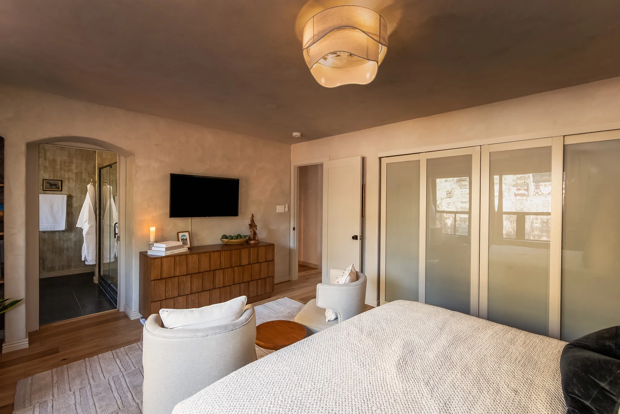Modern bedroom with organic linens, armchairs, and ensuite bathroom view. Luxury Sedona vacation rental.