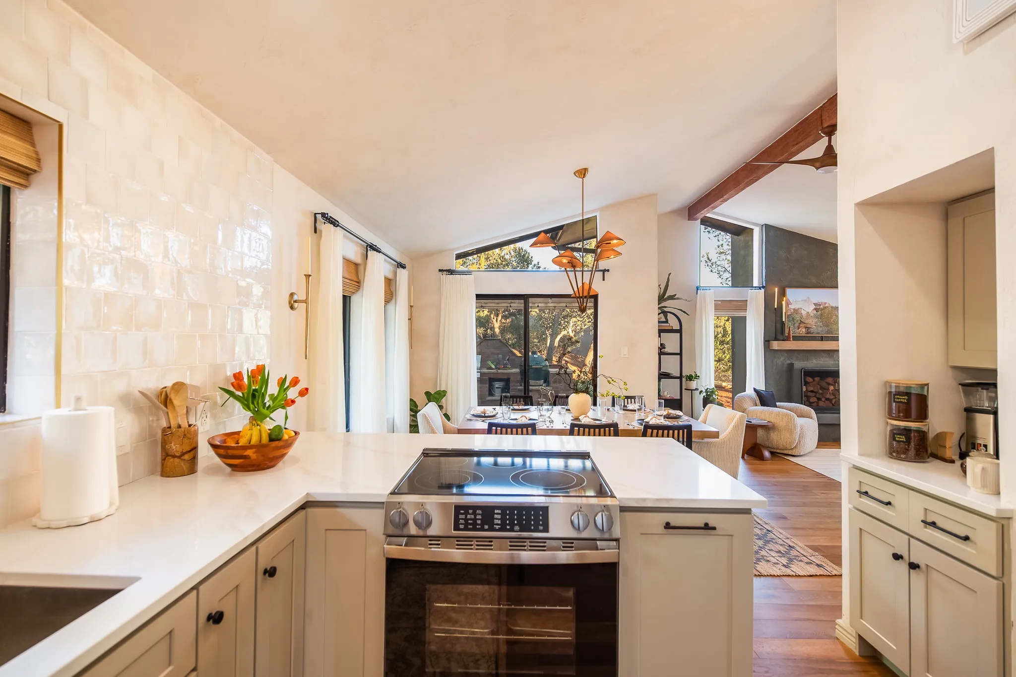 Modern kitchen with white tiles and quartz counters looking into a sunlit dining area in West Sedona.