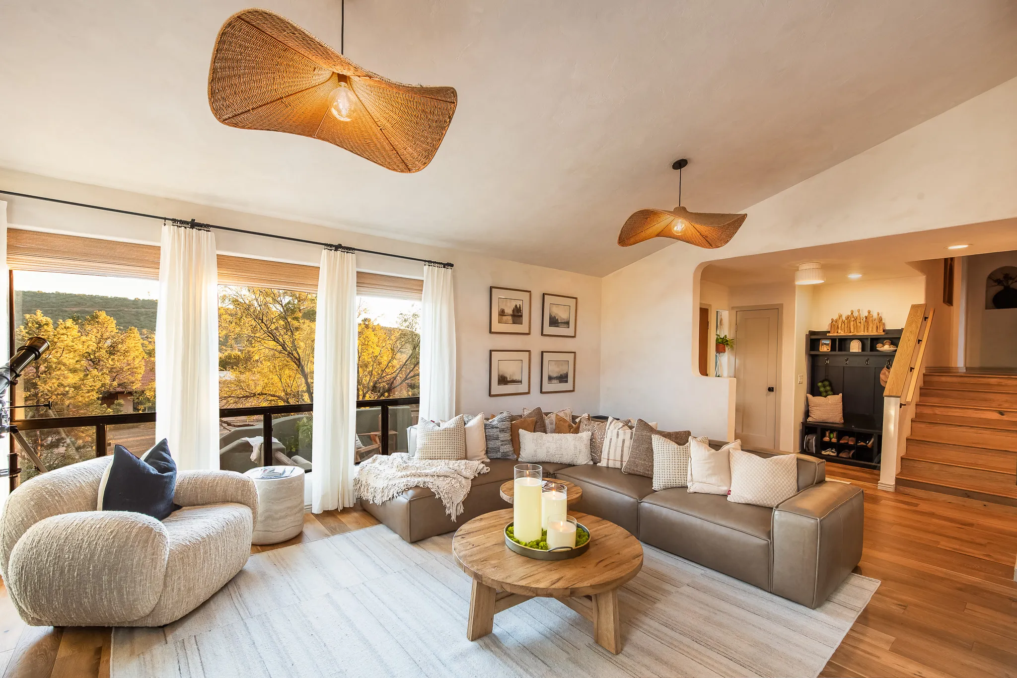 Spacious living room with leather sectional, woven pendant lights, and scenic window views in a West Sedona rental.