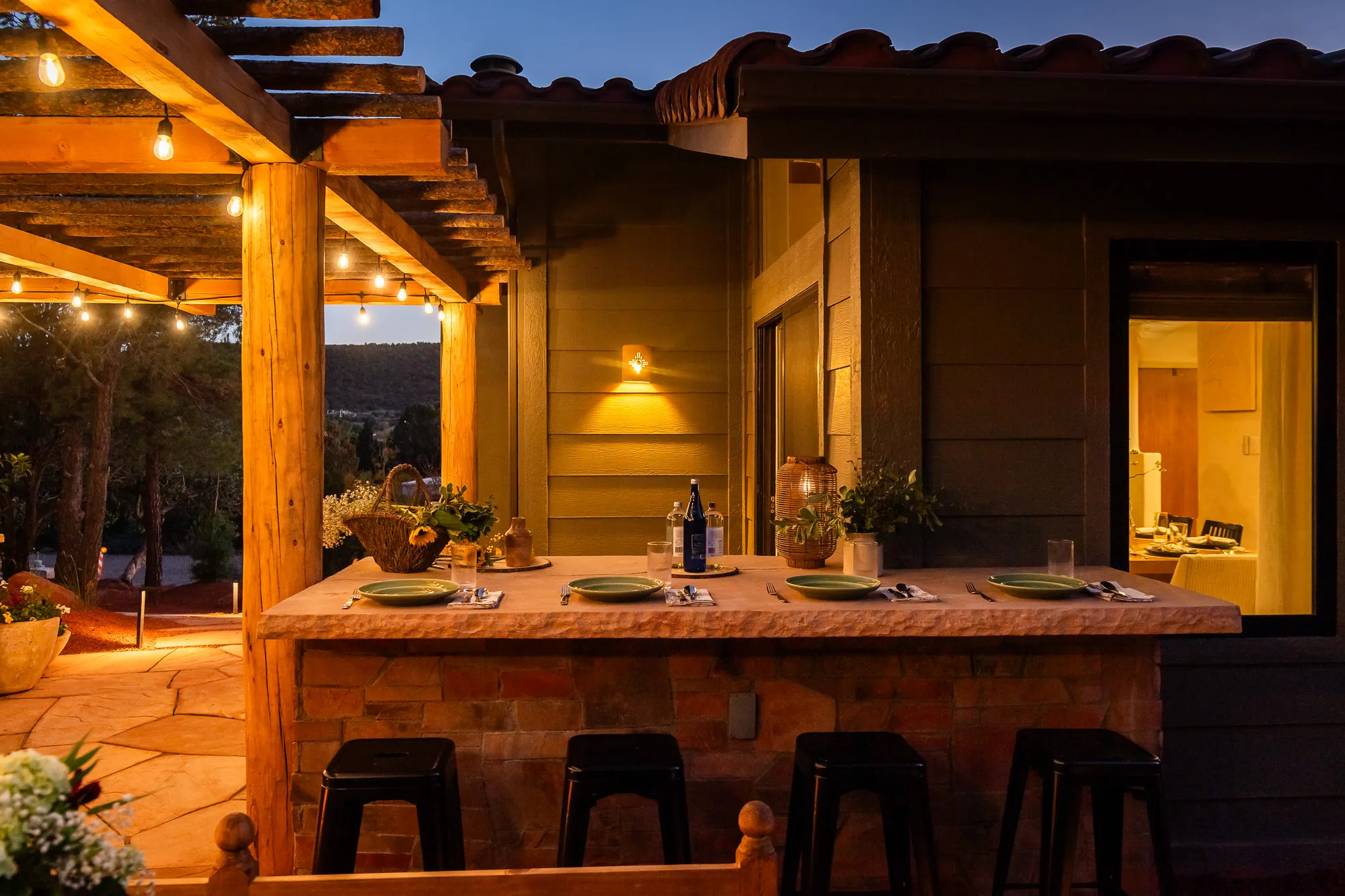 Outdoor stone bar with place settings under a lit pergola at a West Sedona luxury retreat.