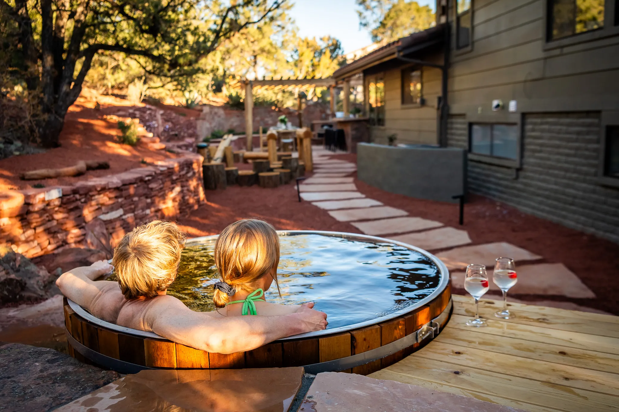 Two people relaxing on lounge chairs by a luxury swimming pool at a West Sedona wellness retreat.