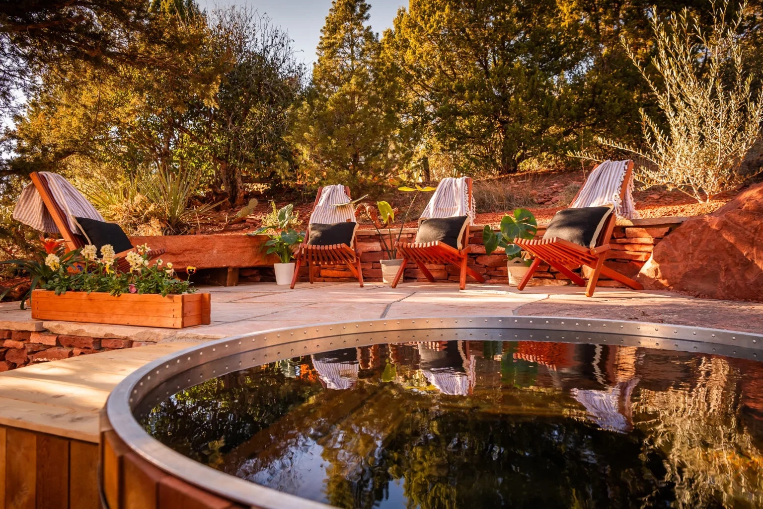 Two thatched-roof bamboo cabanas with orange cushions beside a turquoise swimming pool at a luxury resort.