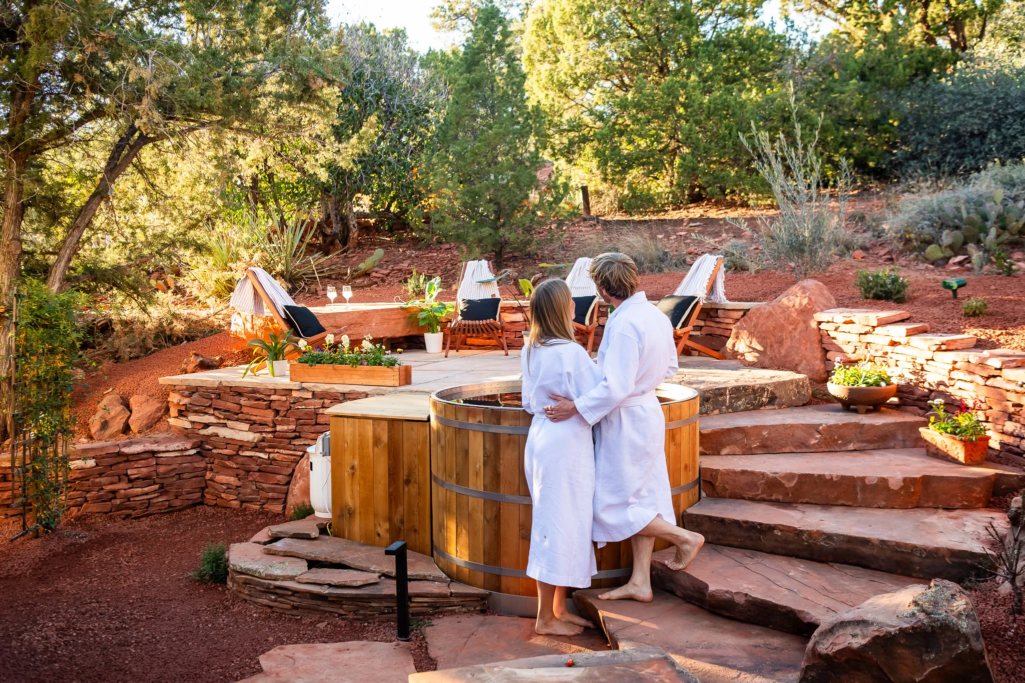 Couple lounging by a blue tiled pool with lush greenery at a Sedona wellness retreat.